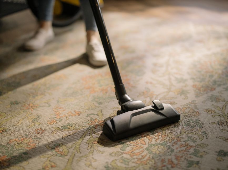 Professional maid service vacuuming a carpeted floor
